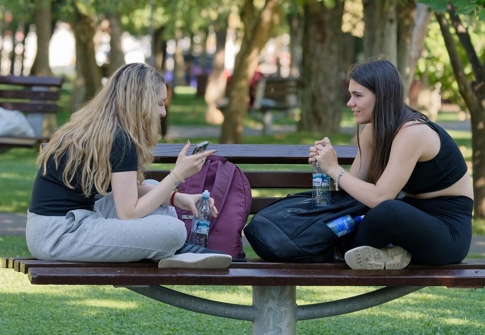 スマホを見ながら会話する若者たち