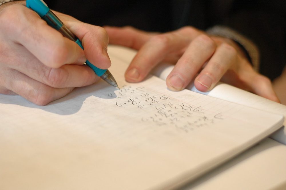 ペンを持って文字を書く手元